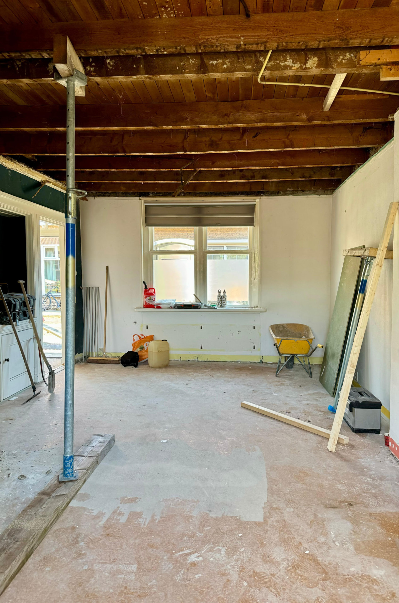 Gestripte woonkamer met vrijgelegd houten plafond en tijdelijke ondersteuning