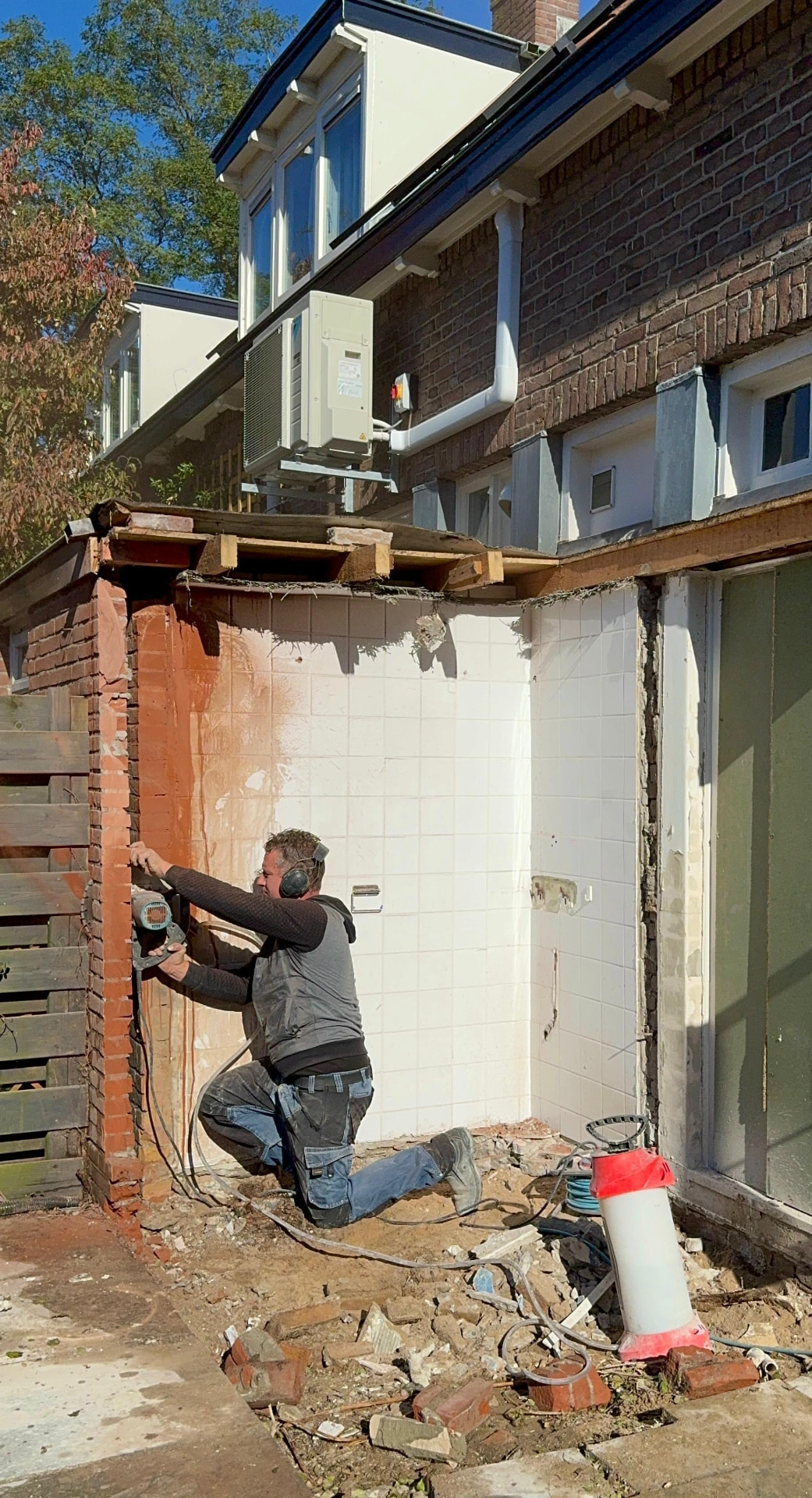 Vakman verwijdert met handgereedschap metselwerk van een aanbouw