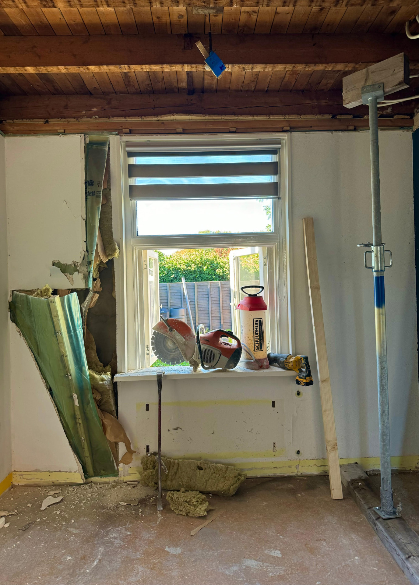 Woninginterieur tijdens renovatiesloop met plafondstempels en vrijgelegde constructie