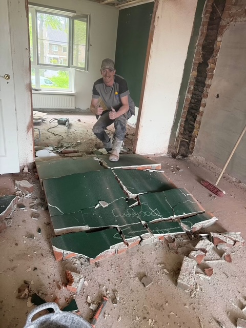 Medewerker in een woning waar binnenwanden en afwerking zijn verwijderd voor renovatie